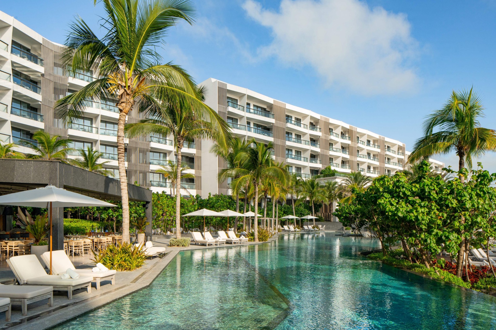 Alberca rodeada de palmeras y arquitectura hotelera en la Riviera Maya